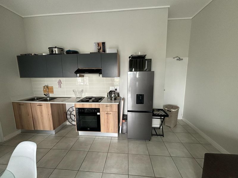 A functional kitchen featuring modern two-tone cabinetry, a built-in oven with hob, extractor fan, and tiled flooring.