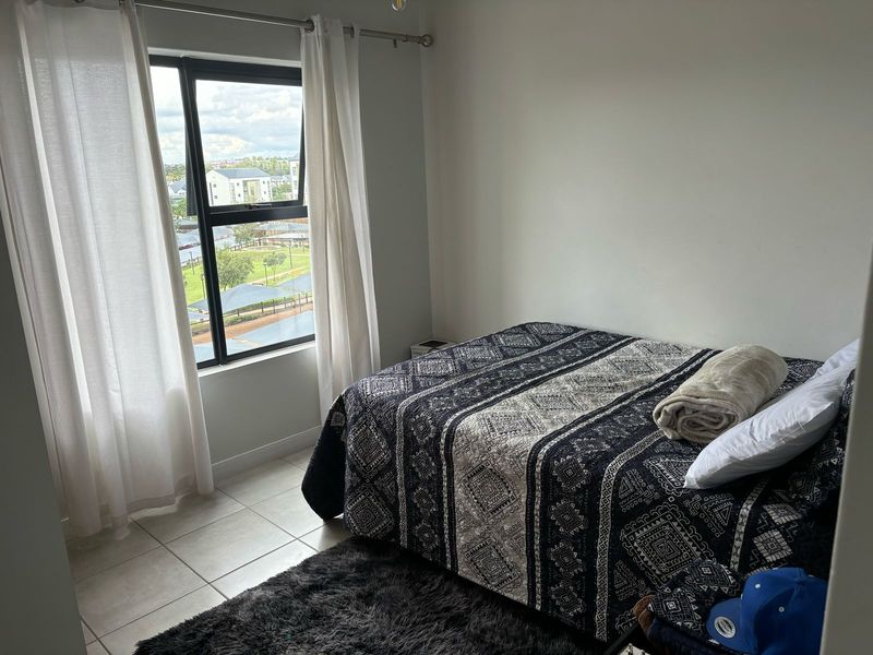 A bedroom featuring tiled flooring and an aluminium window frame with views of the surrounding estate.