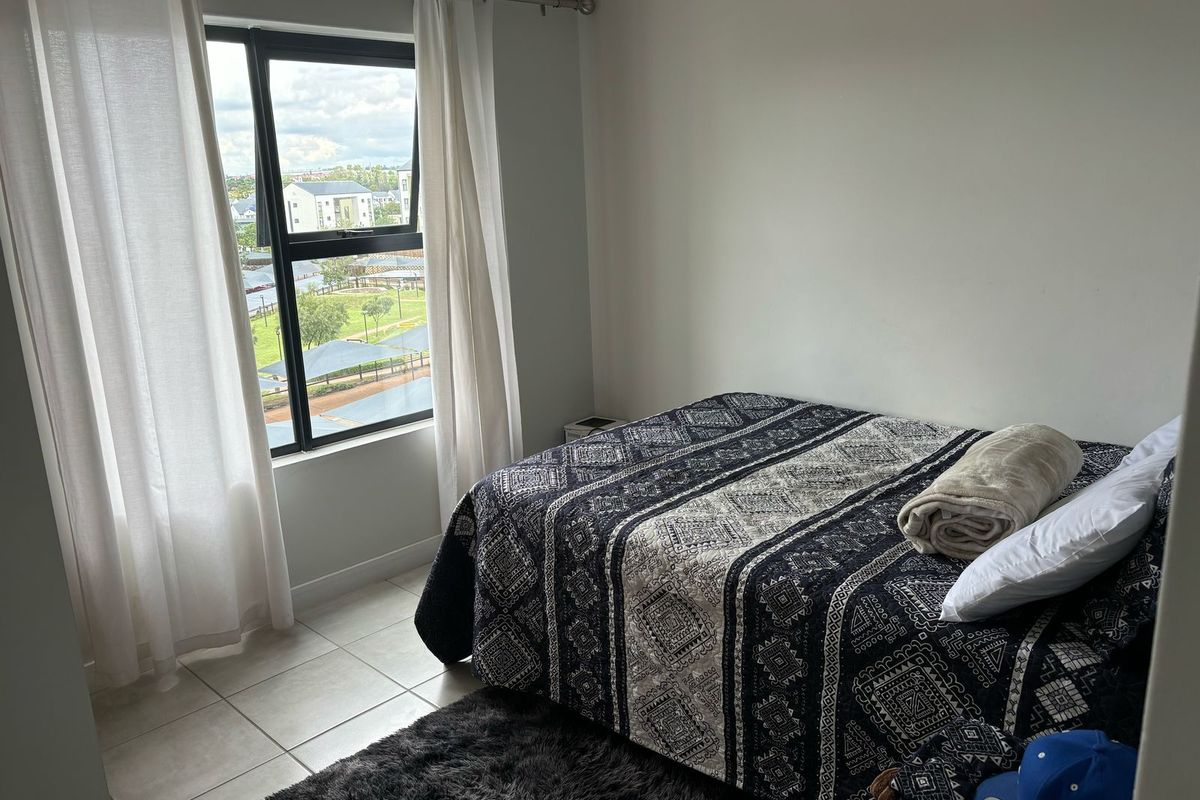 A bedroom featuring tiled flooring and an aluminium window frame with views of the surrounding estate.