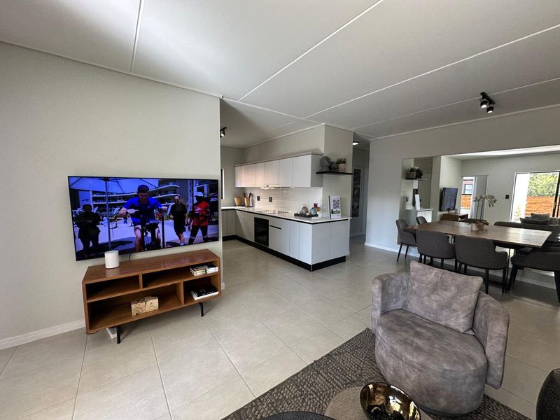 Spacious open-plan living area featuring a modern kitchen with sleek cabinetry, integrated appliances, and neutral tiled flooring throughout.