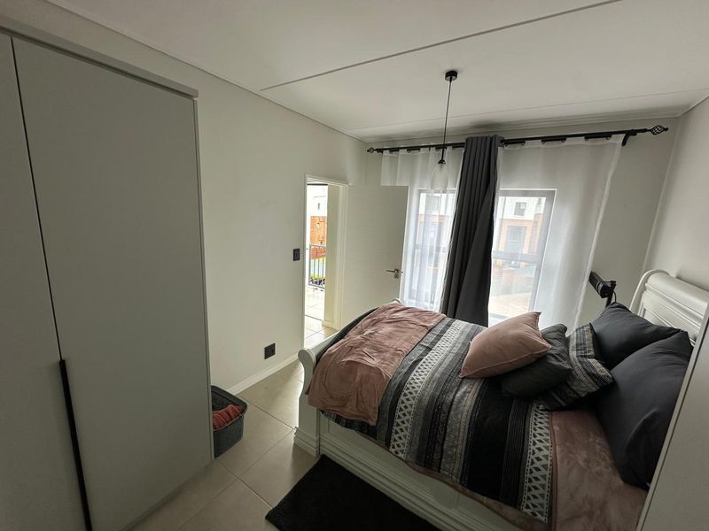 A well-maintained bedroom featuring tiled flooring, a built-in wardrobe, and direct access to an outdoor balcony area.