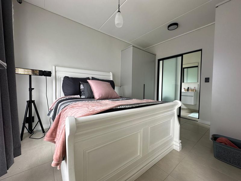 A well-maintained bedroom featuring tiled flooring, built-in wardrobe storage, and an en-suite bathroom accessible through a modern sliding door.
