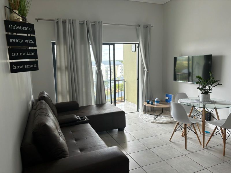 An open-plan living and dining area featuring tiled flooring, neutral walls, and a sliding glass door providing access to a private balcony.