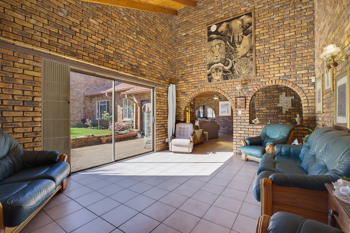 Spacious living room featuring high vaulted timber ceilings, exposed face-brick walls, arched architectural details, and large sliding glass doors opening to a rear patio.