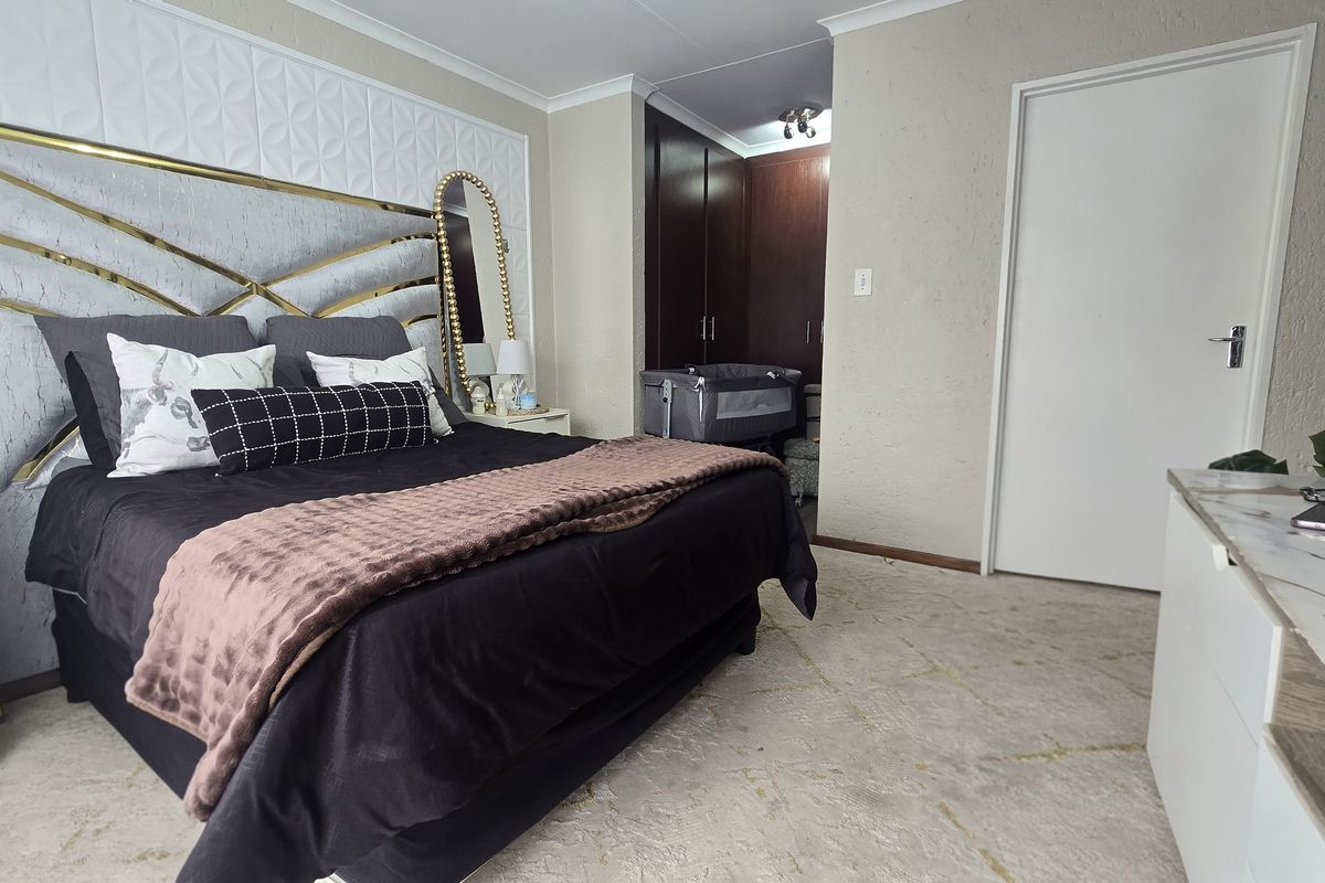 A well-maintained bedroom featuring built-in cupboards, textured wall finishes, and decorative coving, providing a functional and comfortable living space.