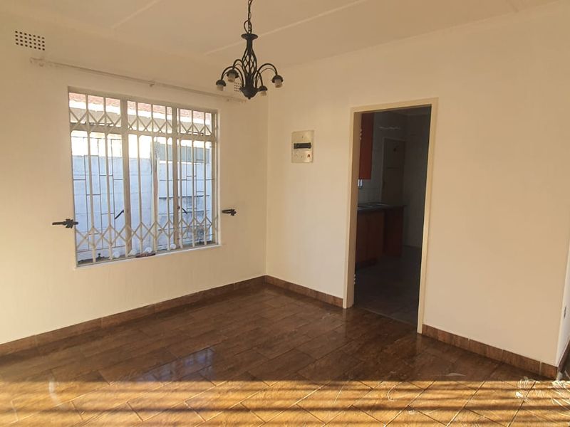 An empty living room featuring tiled flooring, a fireplace with built-in shelving, and a security gate on the window.