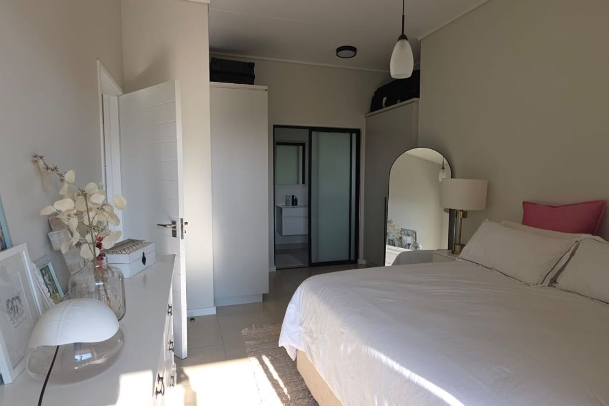 A well-lit bedroom featuring built-in cupboards and an en-suite bathroom with a sliding door entrance.
