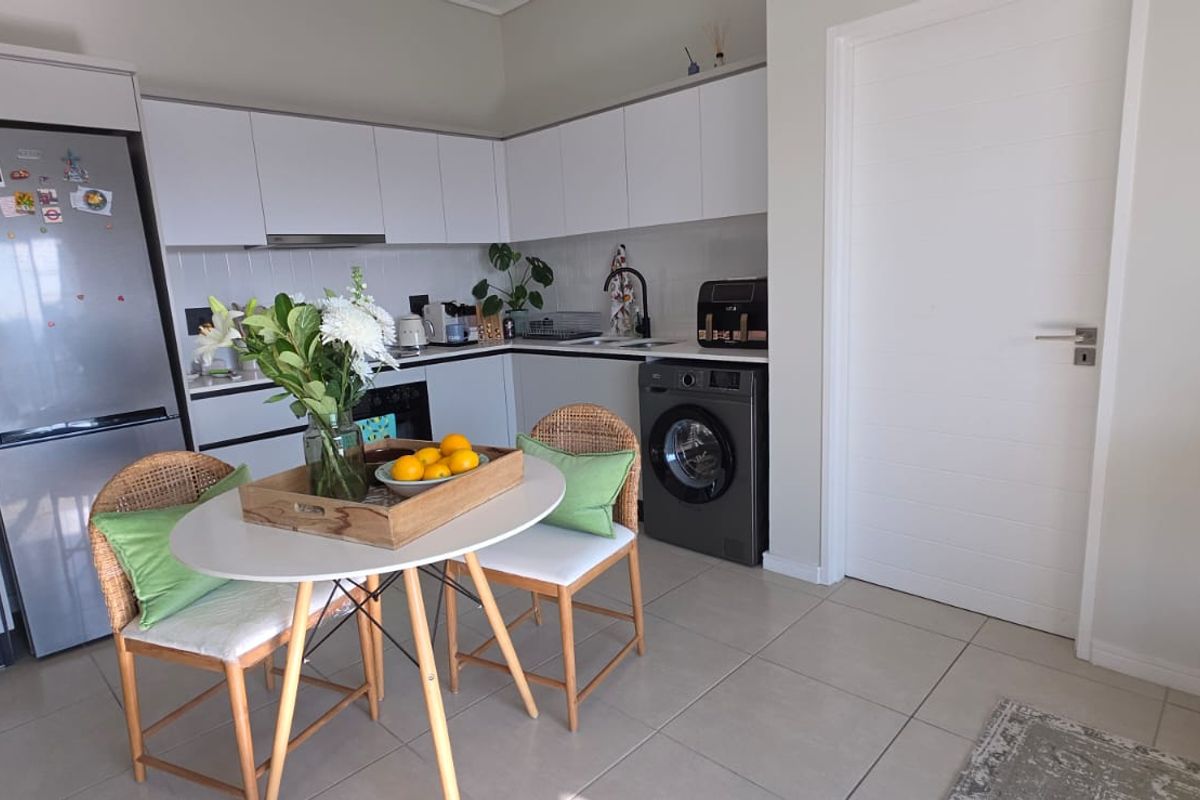 Modern kitchen featuring white cabinetry, integrated appliances, and tiled flooring, seamlessly connected to a dining area.