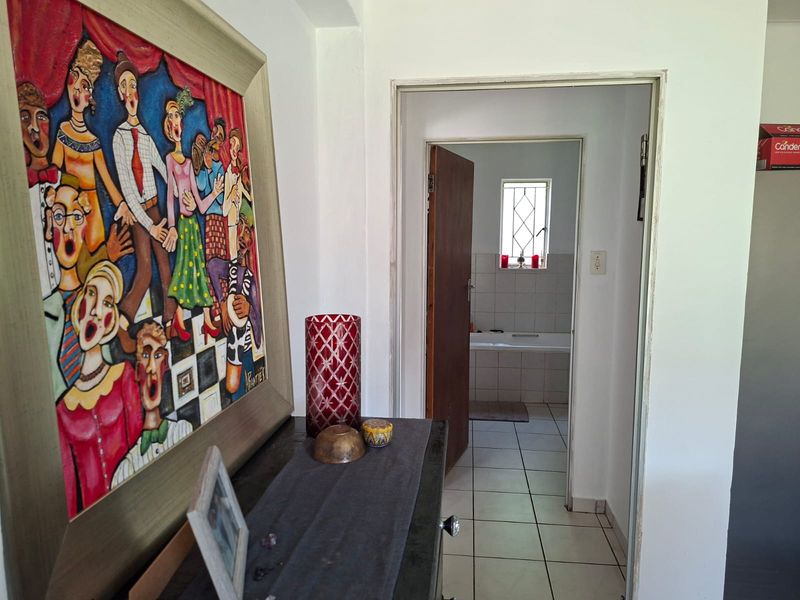 A view through a hallway leading into a bathroom featuring tiled flooring and a window.