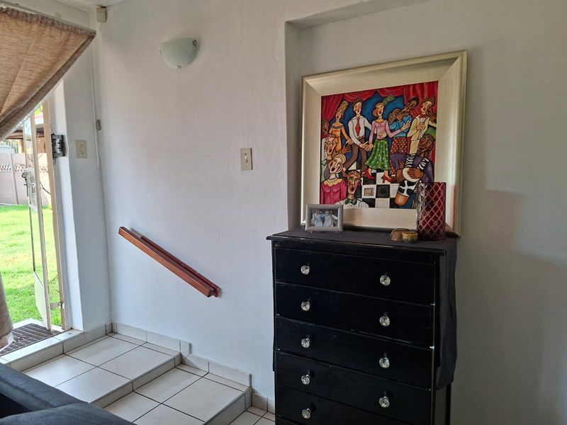 An entry area featuring tiled flooring, a wall-mounted light, and a wooden handrail leading to an exterior glass door.