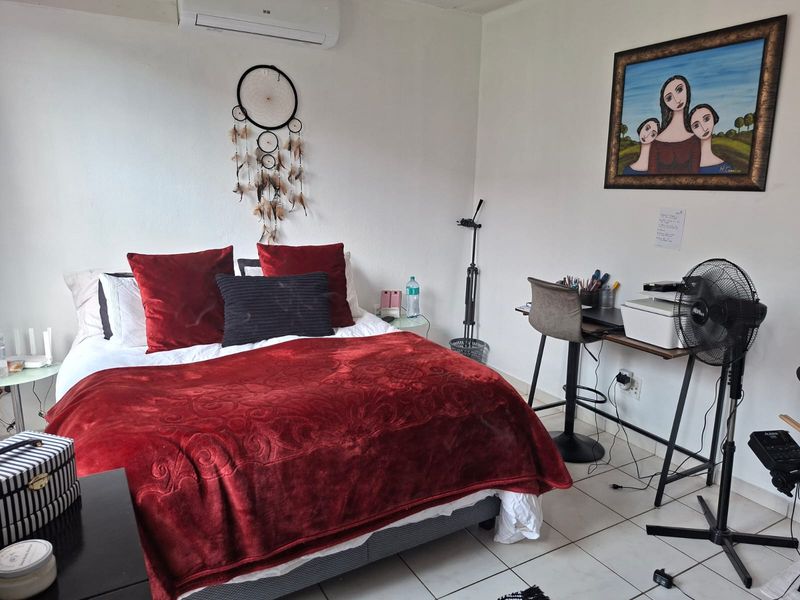A functional bedroom featuring tiled flooring and a wall-mounted split-system air conditioning unit.