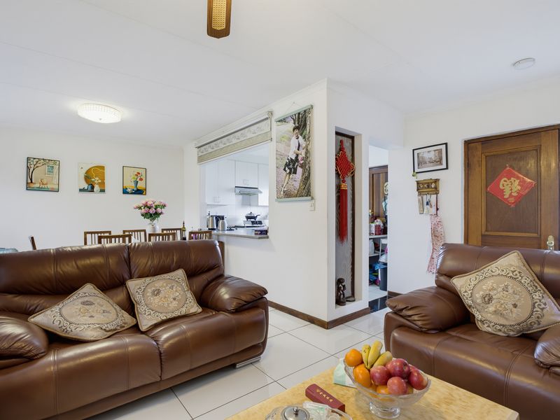 Open-plan living area featuring tiled flooring, a ceiling fan, and a convenient pass-through window connecting to the kitchen space.