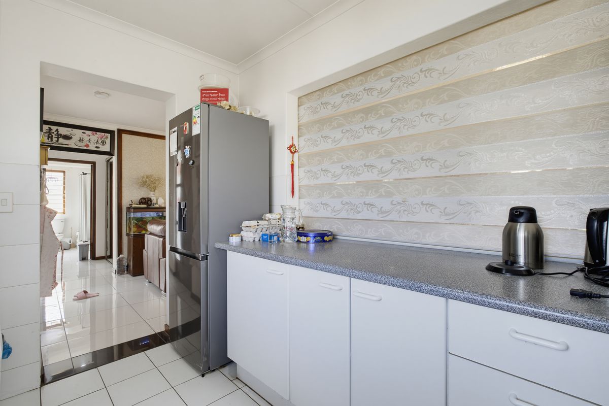A functional kitchen area featuring white cabinetry, grey laminate countertops, and tiled flooring, providing a clean and practical workspace.