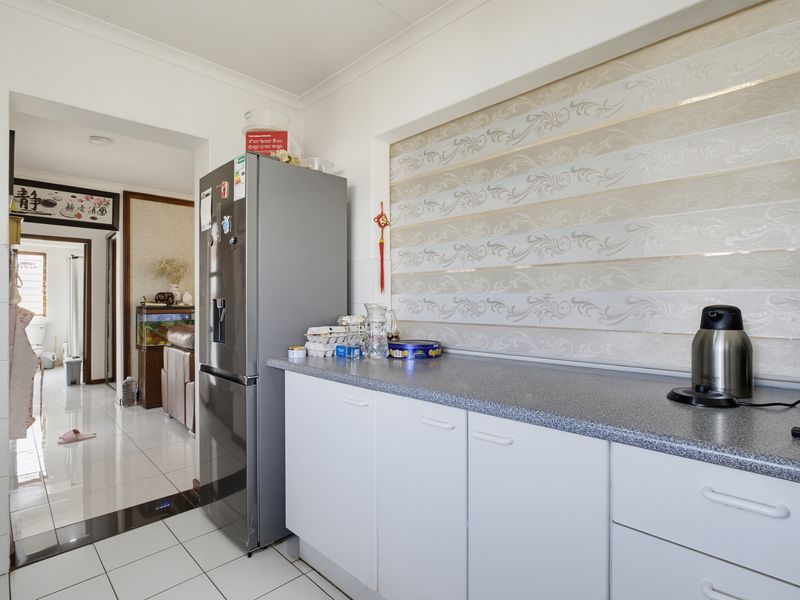 A functional kitchen area featuring white cabinetry, grey laminate countertops, and tiled flooring, providing a clean and practical workspace.