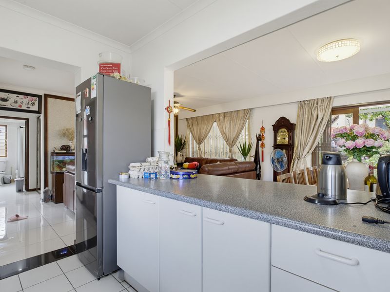 Open plan kitchen area featuring laminate countertops and white cabinetry, seamlessly flowing into the adjacent living space with tiled flooring throughout.