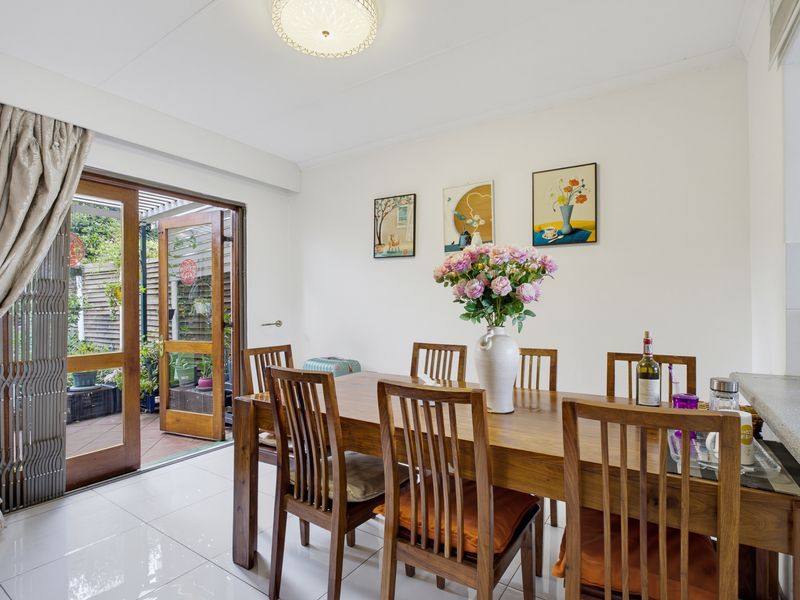 A bright dining area featuring tiled flooring and a sliding glass door providing direct access to an outdoor patio space.
