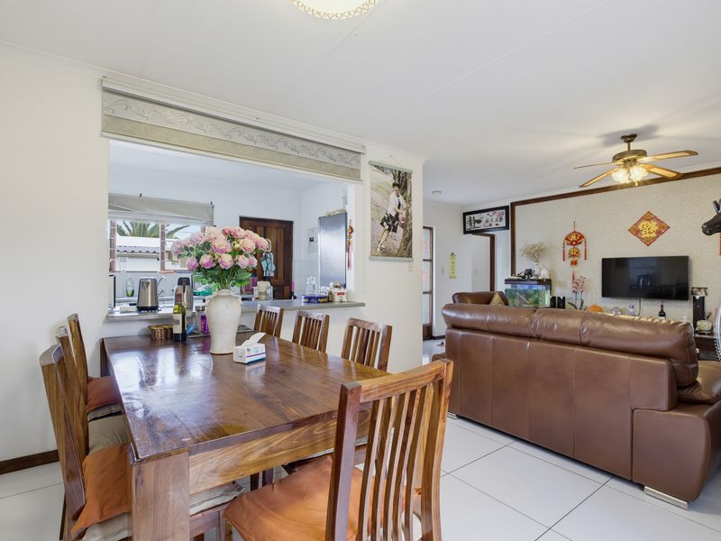 Open-plan living and dining area featuring tiled flooring, a ceiling fan, and a convenient pass-through window connecting to the kitchen.