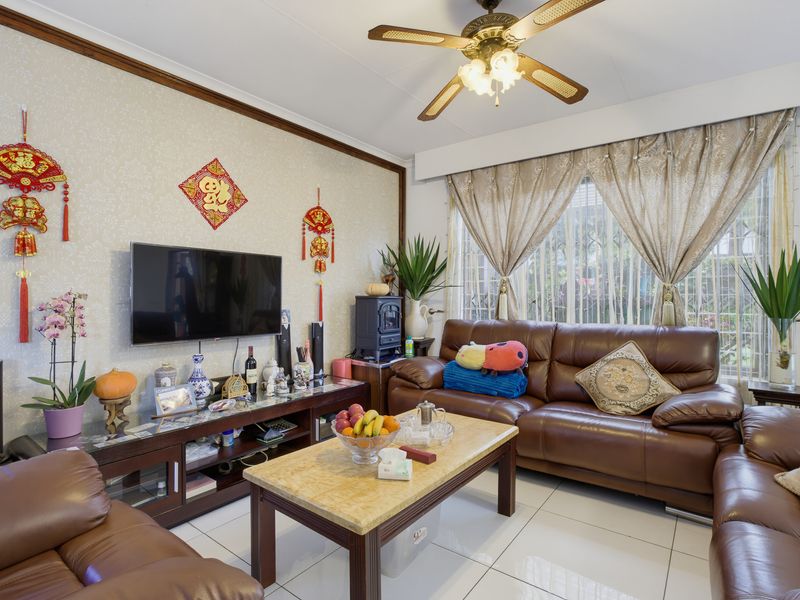 A comfortable living room featuring tiled flooring, a ceiling fan, and decorative crown molding, providing a functional and well-maintained space.