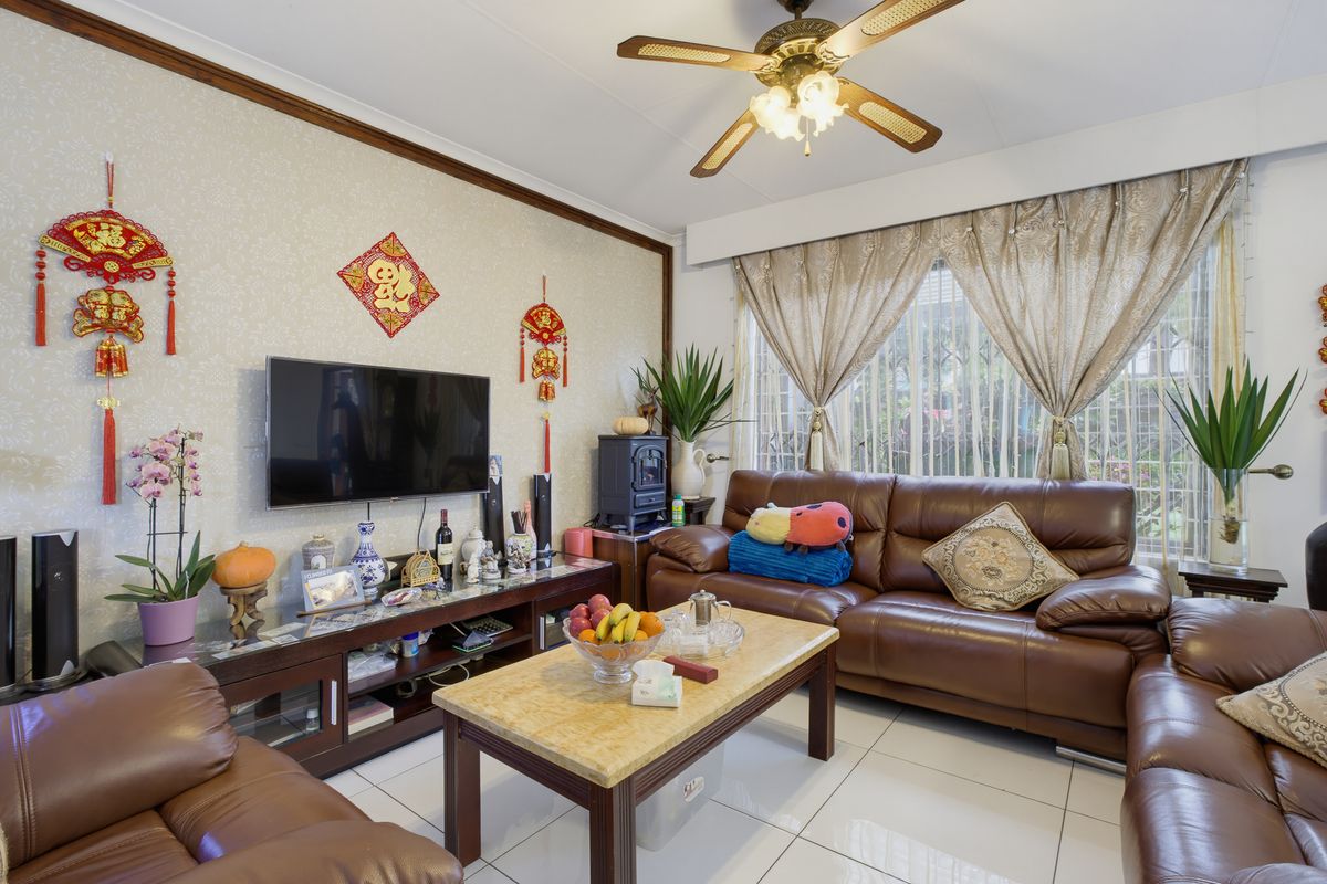 A comfortable living room featuring tiled flooring, a ceiling fan, and decorative crown molding, providing a functional and well-maintained space.