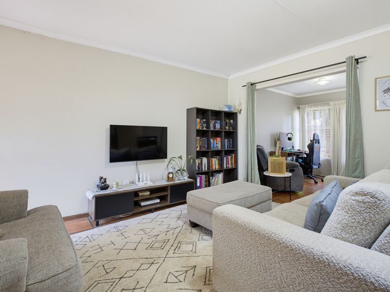 A comfortable living room featuring neutral walls, tiled flooring, and an open transition to an adjacent office space.