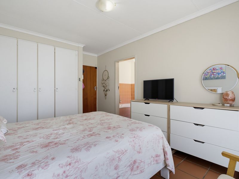 A functional bedroom featuring built-in cupboards, tiled flooring, and direct access to an adjoining bathroom.