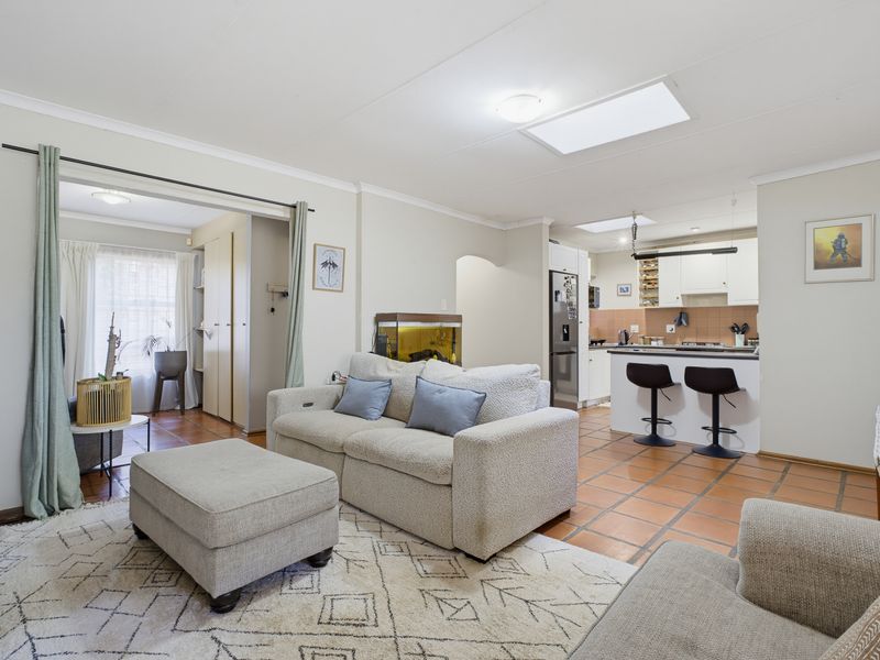 Open-plan living area featuring tiled floors, a functional kitchen with a breakfast bar, and a skylight providing natural light.