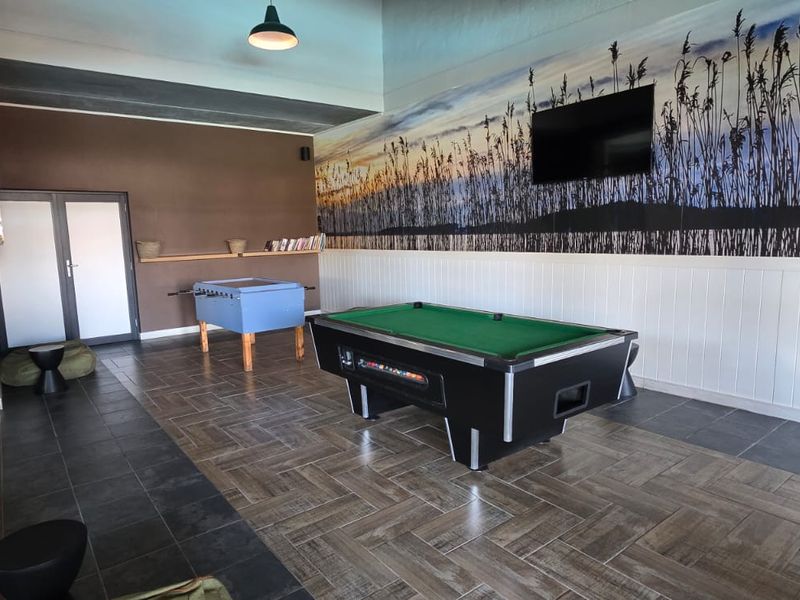 A spacious entertainment room featuring tiled flooring, wainscoting, and a wall-mounted television, designed as a dedicated leisure or cinema space.