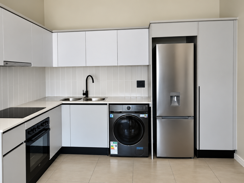 Modern kitchen featuring sleek white cabinetry, quartz countertops, integrated appliances, and a tiled backsplash in a clean, contemporary finish.