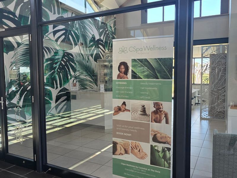 A modern commercial space featuring glass storefront doors, tiled flooring, and a reception area, currently utilized as a wellness facility.