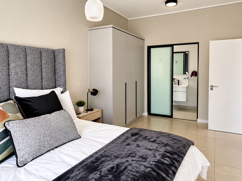 Modern bedroom featuring tiled flooring, built-in wardrobe, and an en-suite bathroom access through a sliding door.