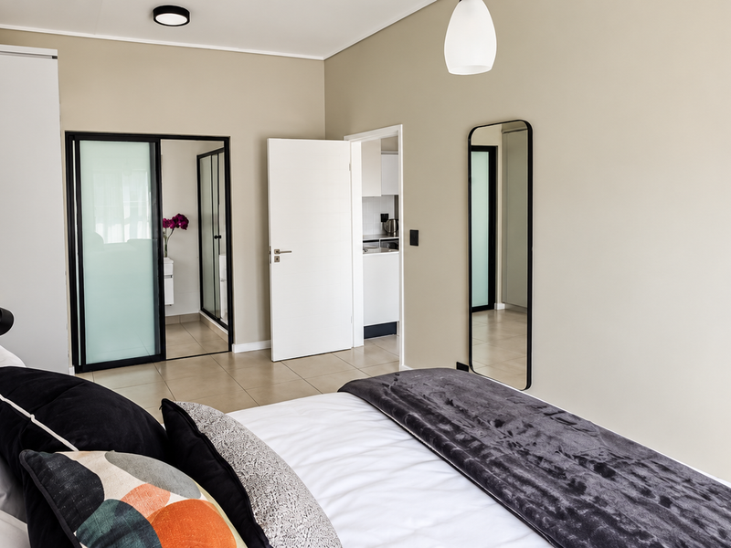 A well-maintained bedroom featuring tiled flooring, built-in wardrobe storage, and neutral wall tones, with direct access to an adjoining bathroom area.