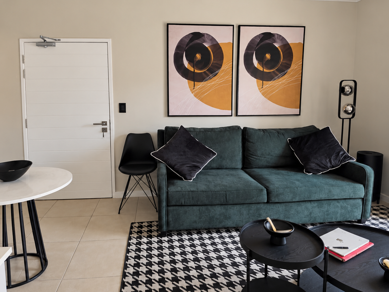 A modern open-plan living area featuring tiled floors, neutral walls, and a sliding glass door providing access to a private balcony.
