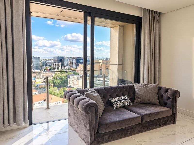 Modern living area featuring large sliding glass doors that open onto a balcony with expansive city views and high-quality tiled flooring.