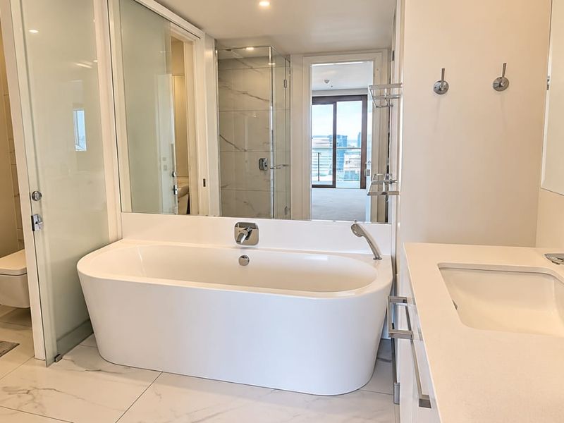 Modern, well-appointed bathroom featuring a sleek freestanding bathtub, glass-enclosed shower, wall-mounted toilet, and a clean vanity with contemporary chrome fixtures.