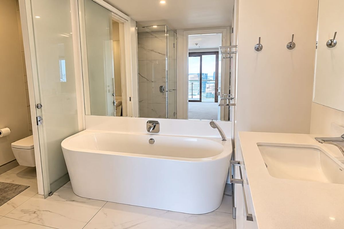 Modern, well-appointed bathroom featuring a sleek freestanding bathtub, glass-enclosed shower, wall-mounted toilet, and a clean vanity with contemporary chrome fixtures.