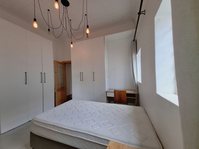 A bedroom featuring extensive built-in white cabinetry, a integrated desk area, and modern pendant lighting, providing ample storage and functional workspace.