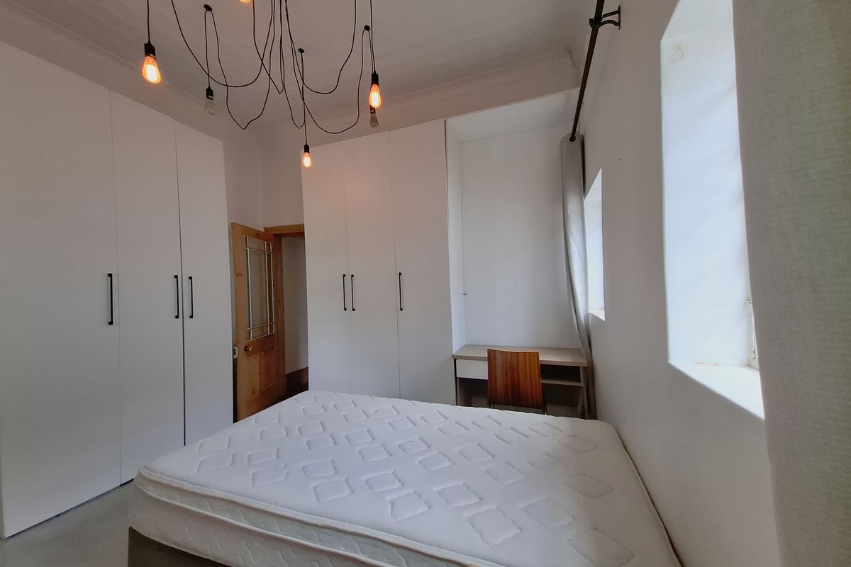 A bedroom featuring extensive built-in white cabinetry, a integrated desk area, and modern pendant lighting, providing ample storage and functional workspace.