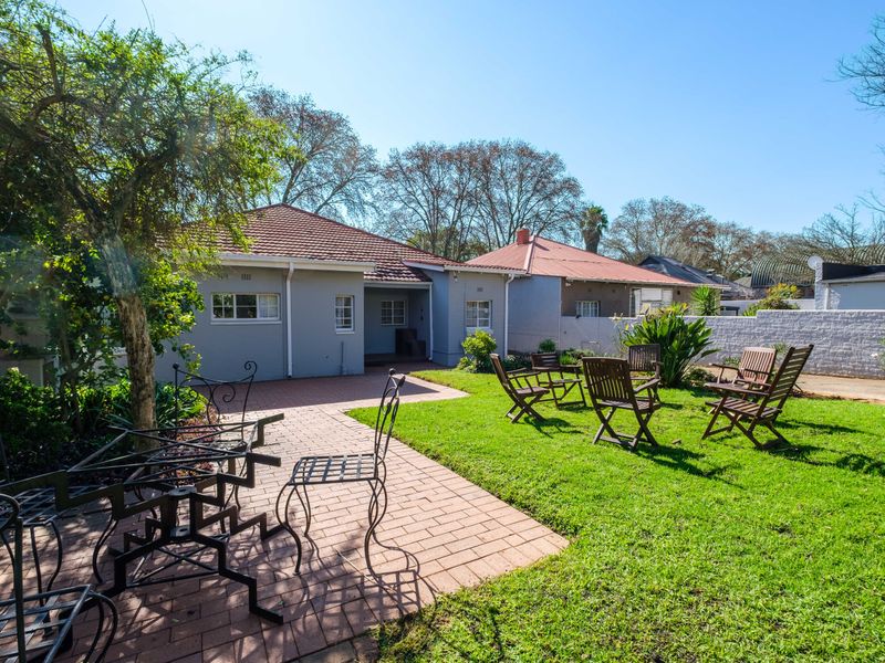 A well-maintained rear garden featuring a brick-paved patio area, lush lawn, and a secure boundary wall, providing a pleasant outdoor space.