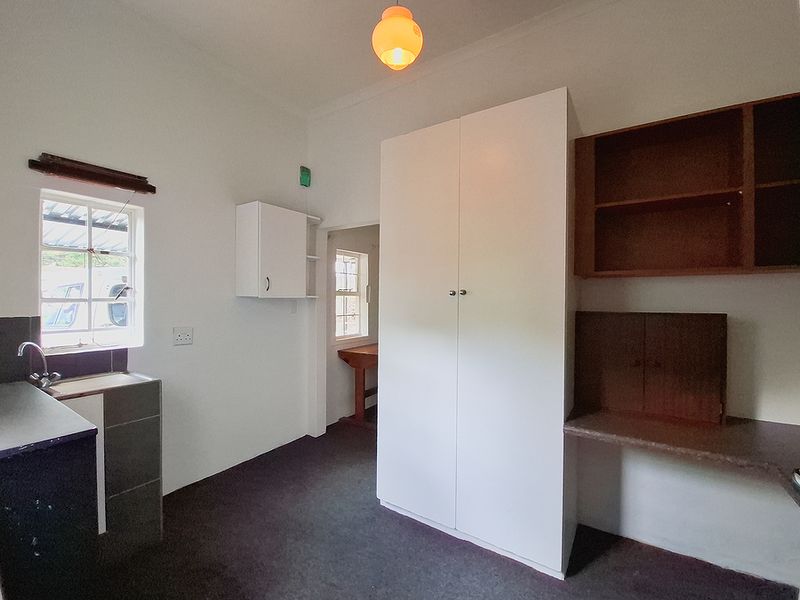A functional scullery area featuring built-in cabinetry, a sink, and additional storage shelving, providing practical utility space for the cottage.