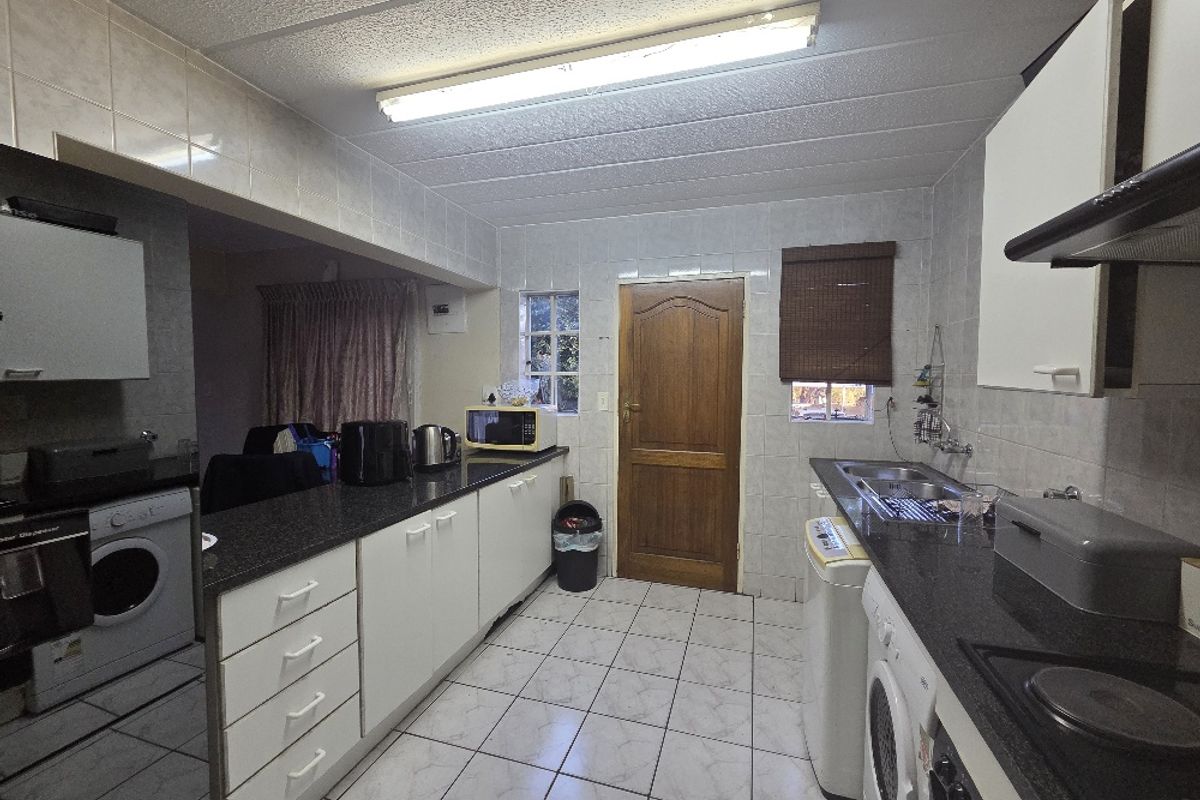 Functional kitchen featuring granite countertops, built-in cabinetry, tiled walls and flooring, and integrated appliances, offering a practical layout for daily use.