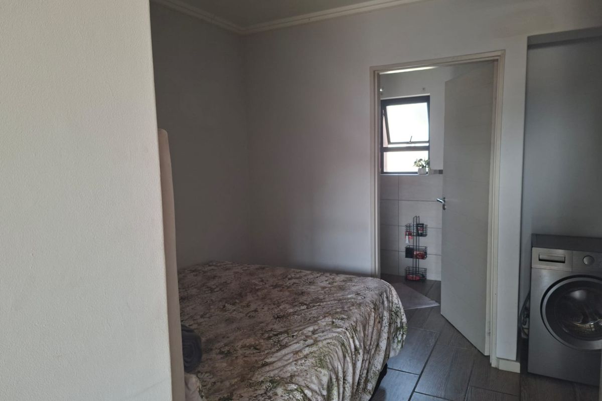 A bedroom featuring tiled flooring and an adjoining doorway leading to a bathroom area.