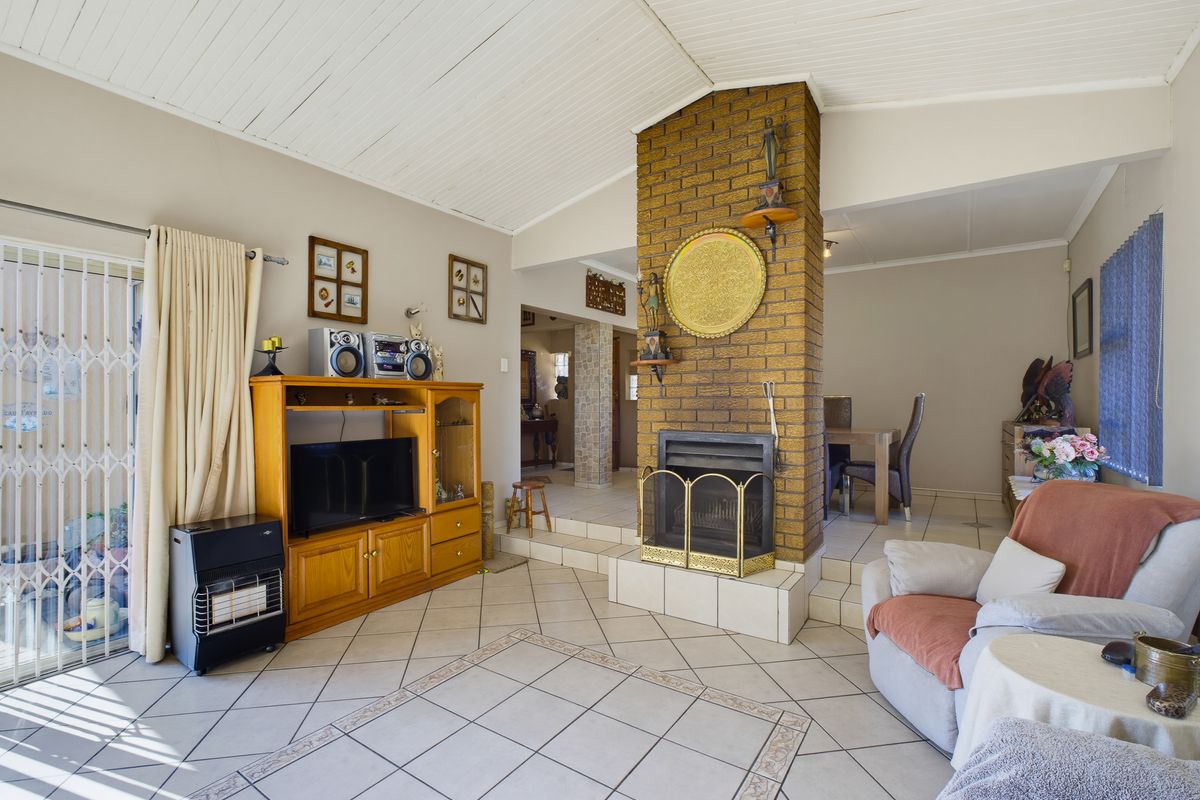 Spacious living area featuring a central brick fireplace, tiled flooring, and sliding glass doors providing access to the exterior.