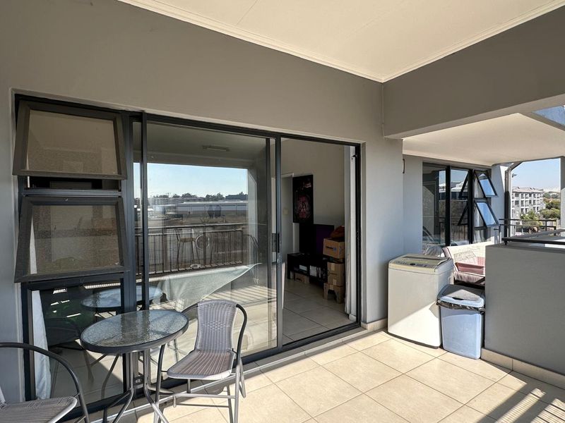 A covered balcony featuring tiled flooring and large sliding glass doors that provide access to the interior living space.