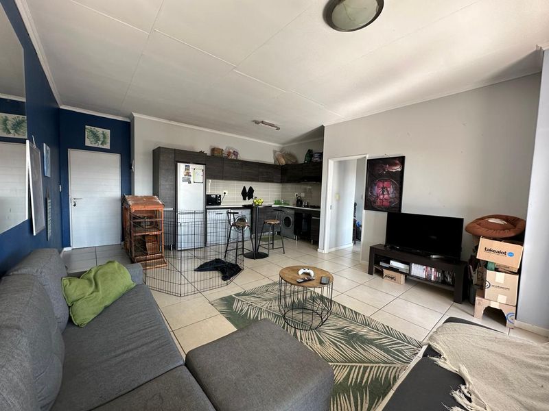 Open-plan living area featuring a functional kitchen with built-in cabinetry and tiled flooring throughout, providing a versatile space for living and dining.