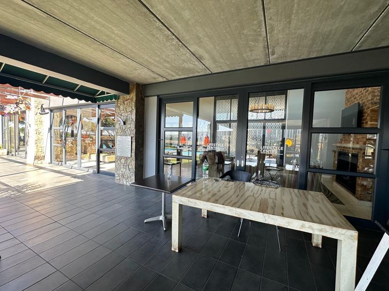 A spacious covered patio featuring dark tiled flooring, an exposed concrete ceiling, and large glass sliding doors providing seamless access to the interior.
