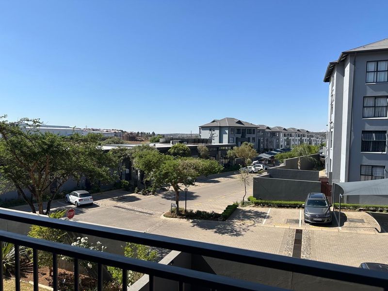 Elevated view overlooking the apartment complex parking area and surrounding neighbourhood landscape from a private balcony.