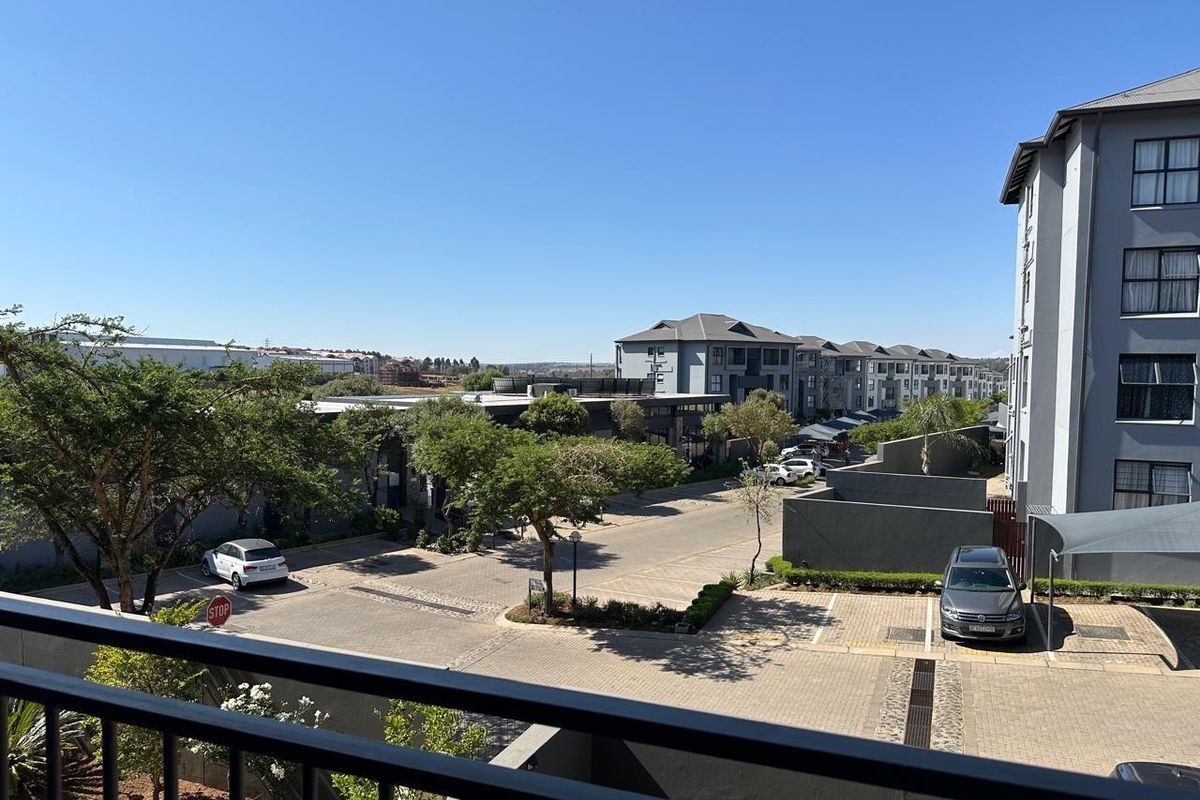 Elevated view overlooking the apartment complex parking area and surrounding neighbourhood landscape from a private balcony.