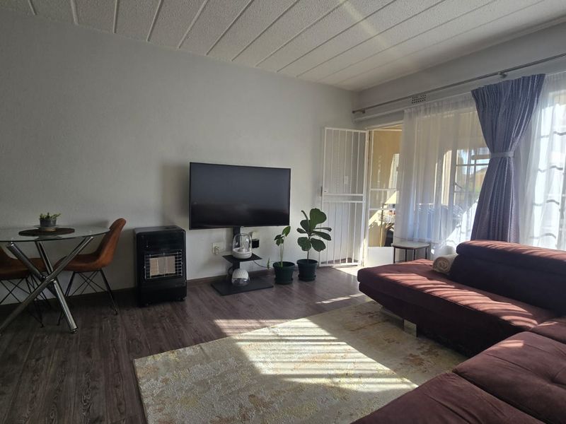 A living room featuring laminate flooring, a security gate, and a sliding glass door providing access to an outdoor area.
