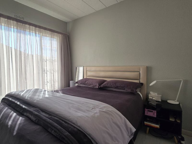 A functional bedroom featuring a built-in wardrobe and a large sliding glass door that provides natural light.