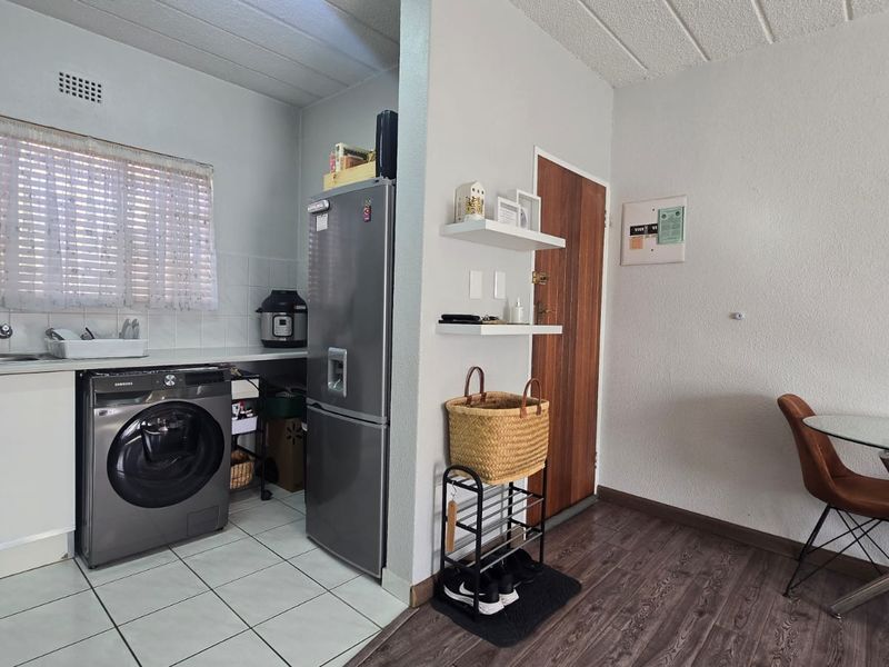 Open plan kitchen and dining area featuring tiled and laminate flooring, functional cabinetry, and a dedicated laundry appliance space.